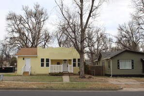 A two-story residential building with a front porch and a small attached garage.