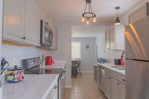 A modern kitchen with stainless steel appliances, a white countertop, and a hanging light fixture. - Chic 4-bed with AC in beautiful Colorado Springs near downtown and pet friendly (Colorado Springs)