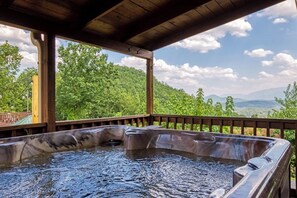 Ein Whirlpool mit Holzterrasse und Blick auf eine Berglandschaft.