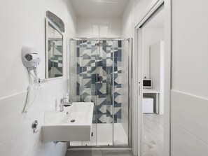 Een moderne badkamer met een douche, een haardroger en een wastafel.