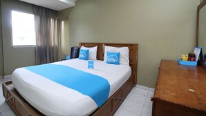 Una habitación de hotel con una cama, una mesita de noche de madera, una ventana con cortinas y un espejo.