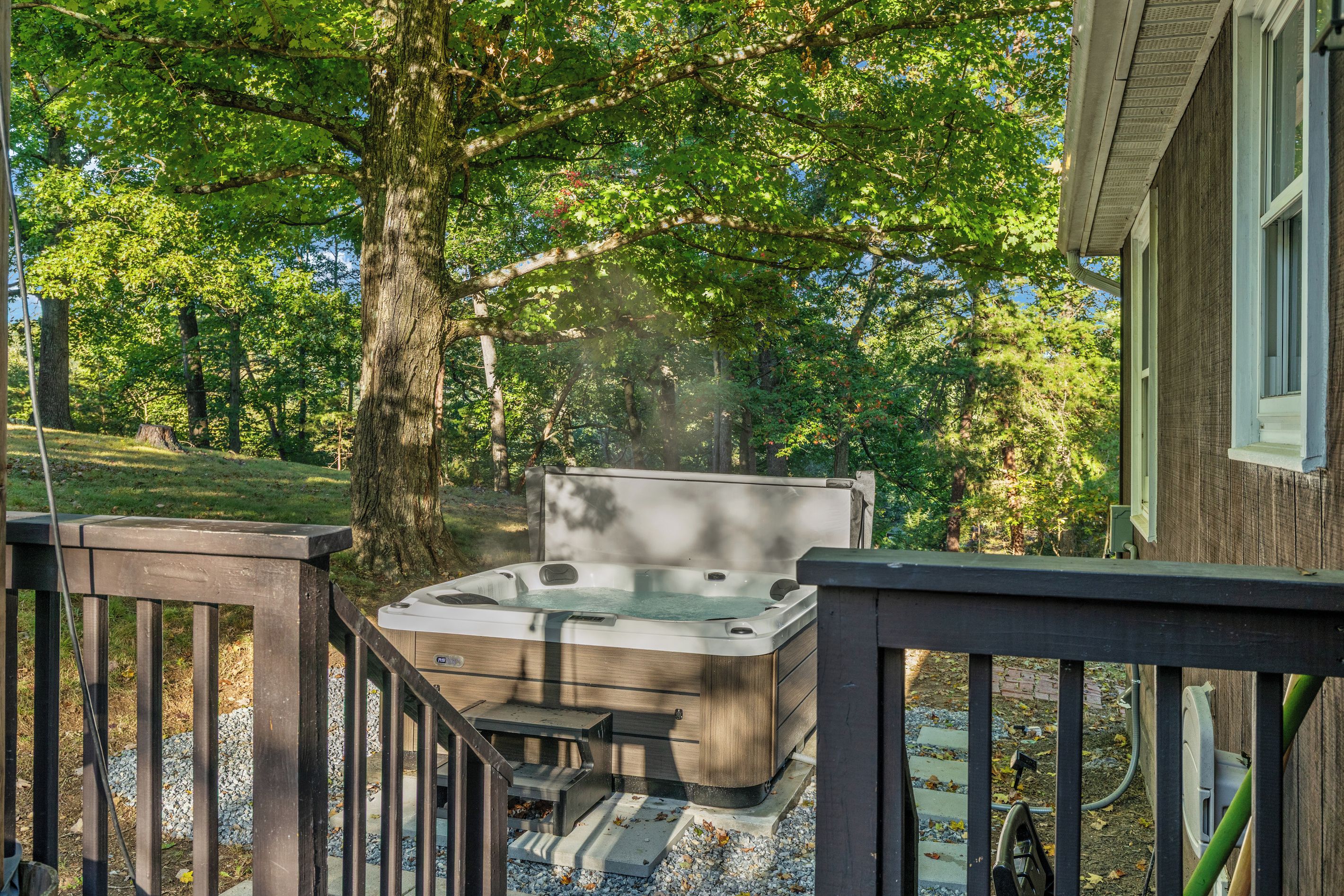 A hot tub on a wooden deck with a view of a forested area.