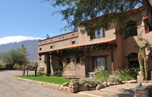 A two-story brick building with a patio area, a cactus, and a mountain backdrop.