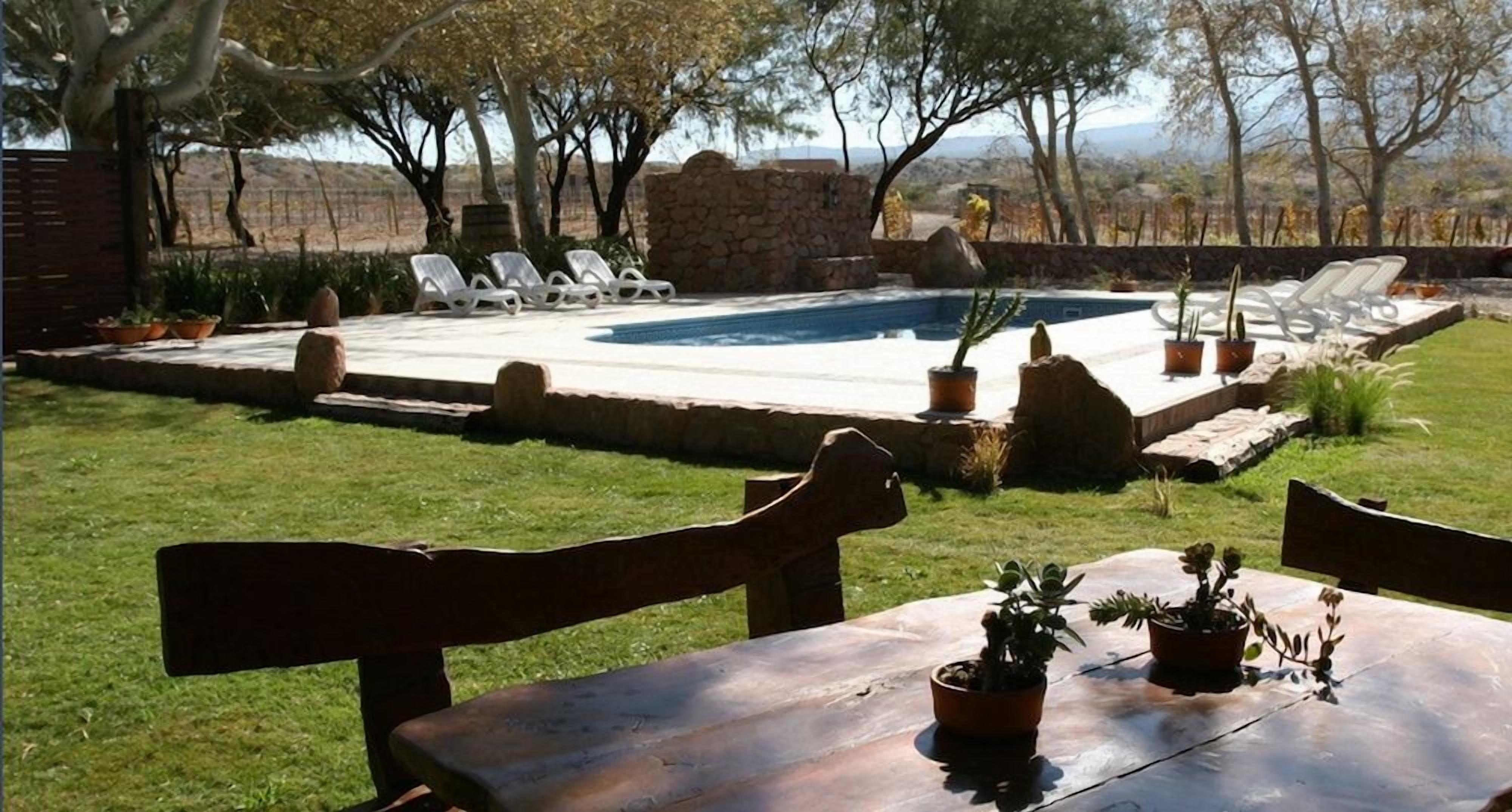 A pool area with lounge chairs, a stone wall, and potted plants.