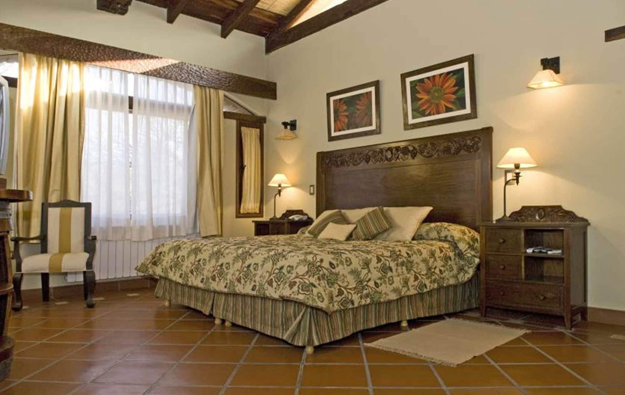 A bedroom with a large bed, two bedside lamps, a chair, and a nightstand.