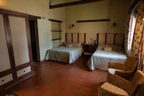 A room with two beds, a chair, and a tiled floor.