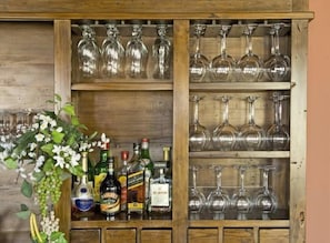 A wooden cabinet with shelves holding various bottles and glasses.