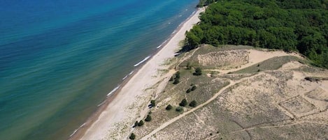 Vue aérienne d’une zone côtière avec une plage et une zone boisée.