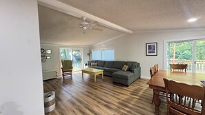 Ein geräumiges Wohnzimmer mit einer Eckcouch, einem Esstisch mit Stühlen und einem Deckenventilator.