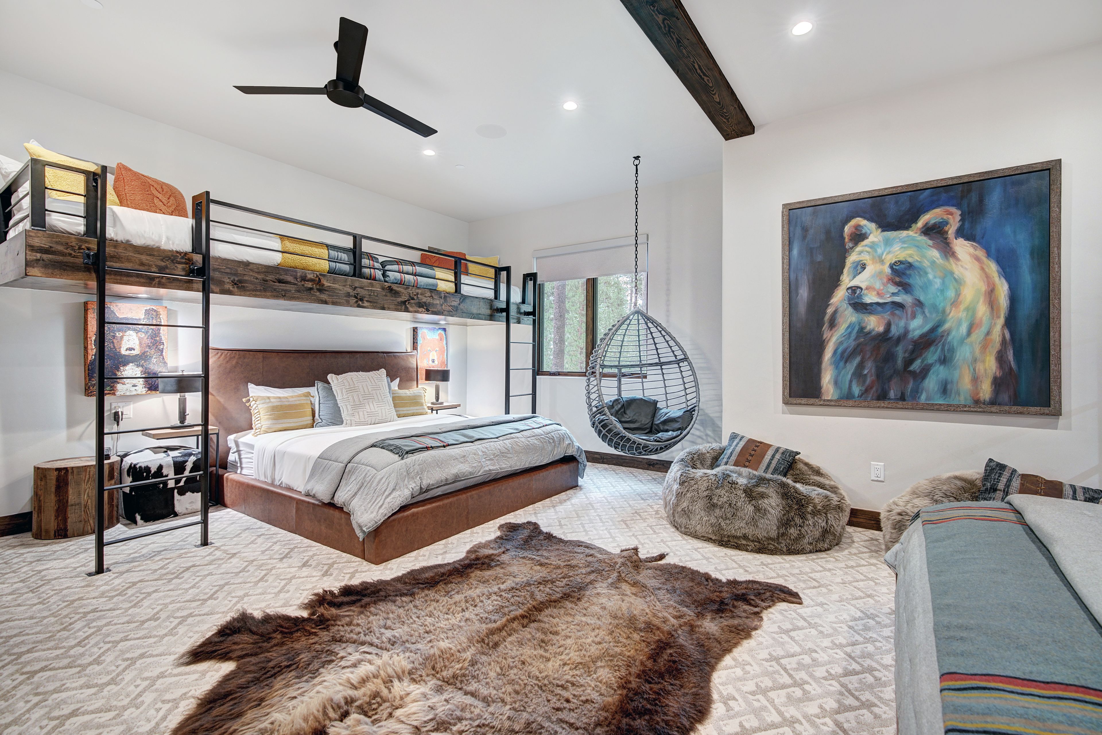 A modern bedroom with bunk beds, a hanging chair, a rug, and a bear painting.