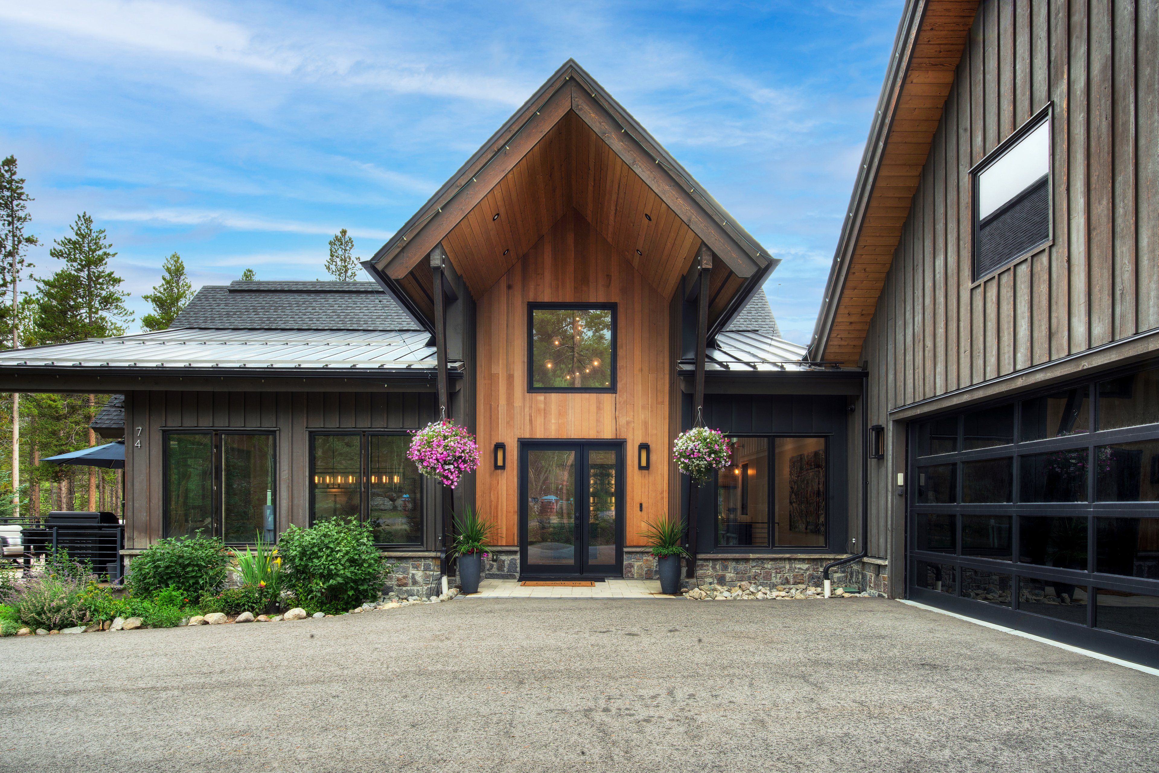 A modern building with a prominent wooden gable, large windows, and a garage.