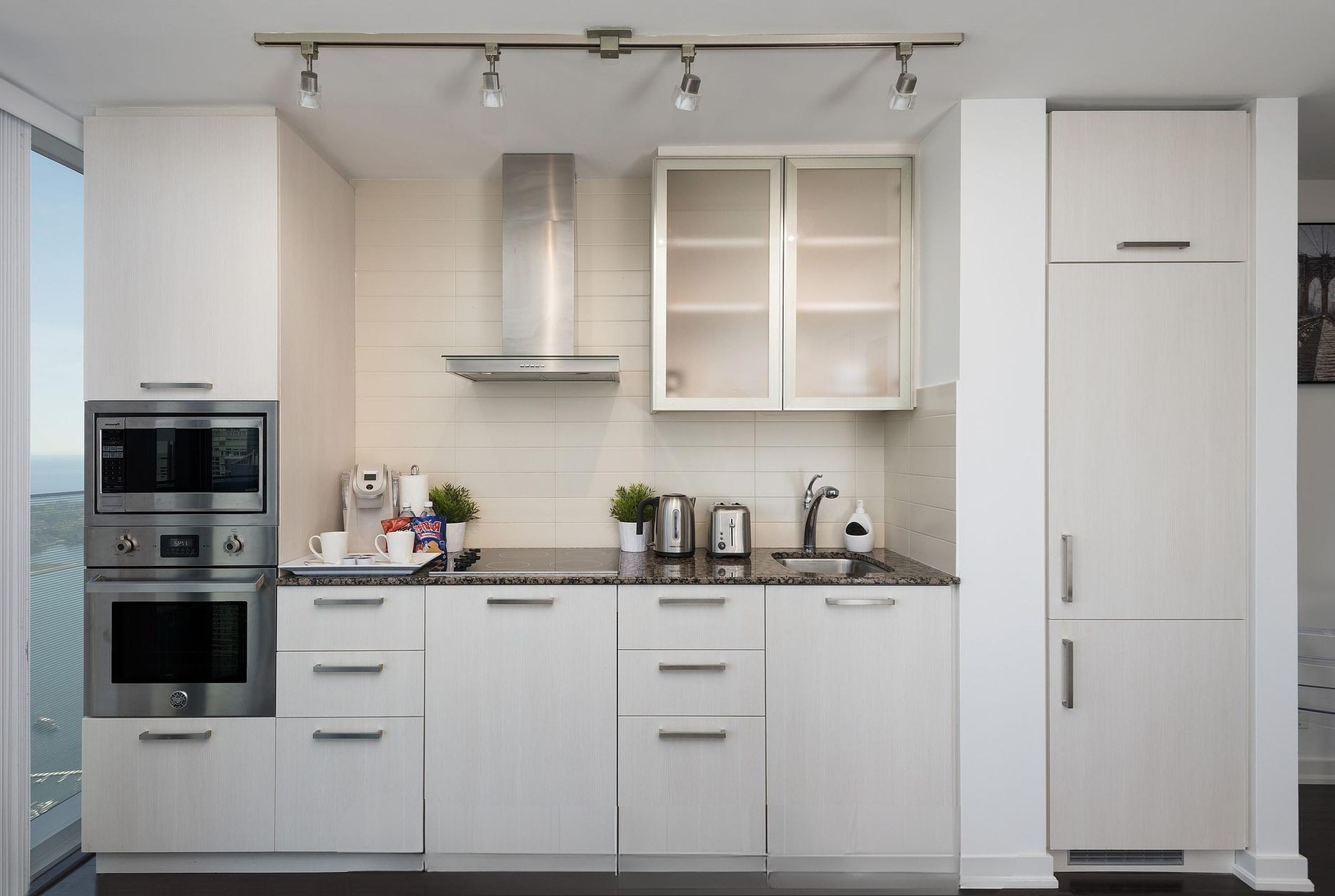 A modern kitchen with white cabinetry, stainless steel appliances, and a granite countertop.