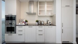 A modern kitchen with white cabinetry, stainless steel appliances, and a granite countertop. - Skyline Suite Near CN Tower Downtown (Toronto)