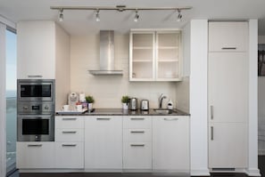 Uma cozinha moderna com armários brancos, eletrodomésticos de aço inoxidável e bancada de granito.