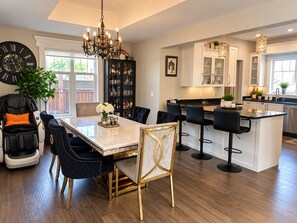A modern kitchen with a central island, bar stools, and a dining area with a chandelier. -     Cottage Charm Meets Modern Comfort in the Heart of Woodstock (Woodstock)