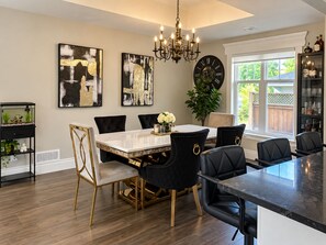 A dining area with a marble table, black upholstered chairs, a chandelier, and abstract artwork on the walls. -     Cottage Charm Meets Modern Comfort in the Heart of Woodstock (Woodstock)