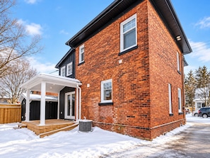 A two-story brick house with a covered porch and a garage. -     Cottage Charm Meets Modern Comfort in the Heart of Woodstock (Woodstock)