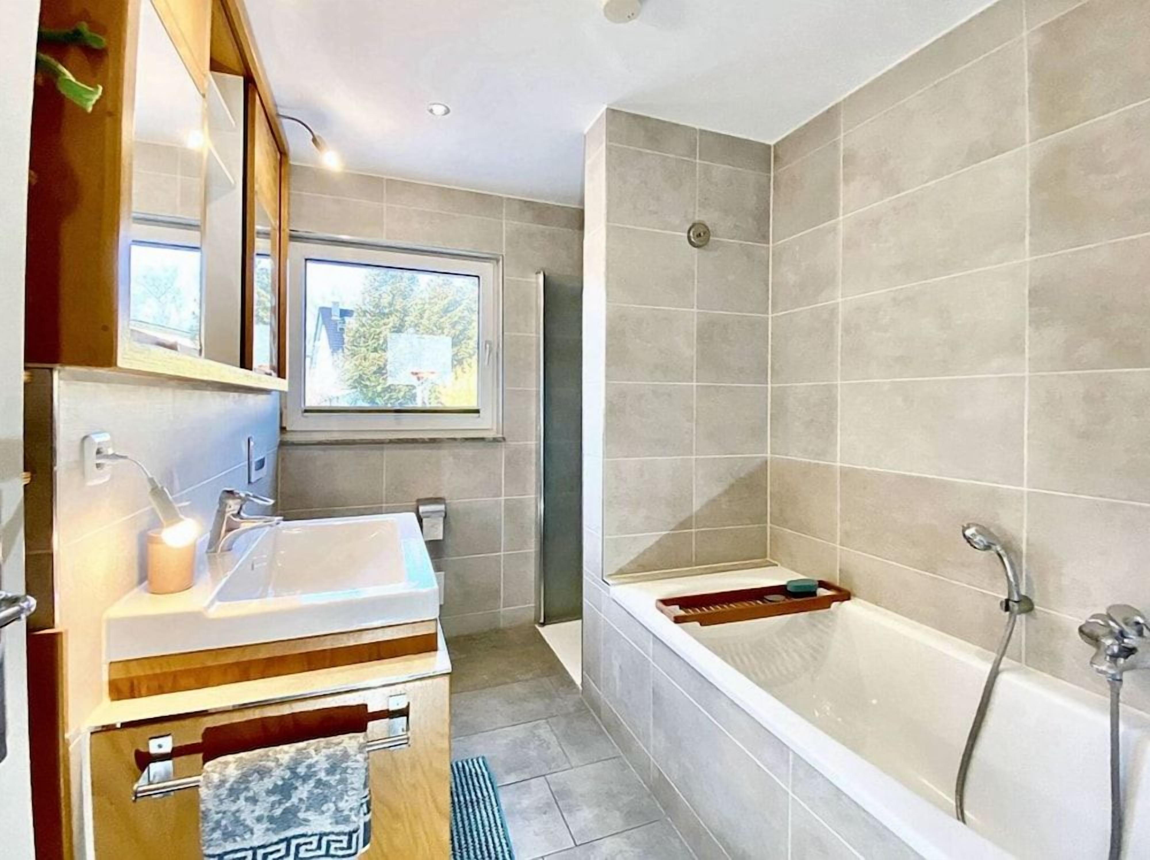 Ein modernes Badezimmer mit einer Badewanne, einem Waschbecken und einem Fenster.