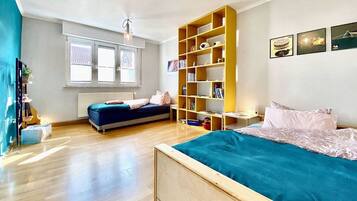 Ein Schlafzimmer mit einem Bett, einem Sofa, einem Bücherregal und einem Fenster.