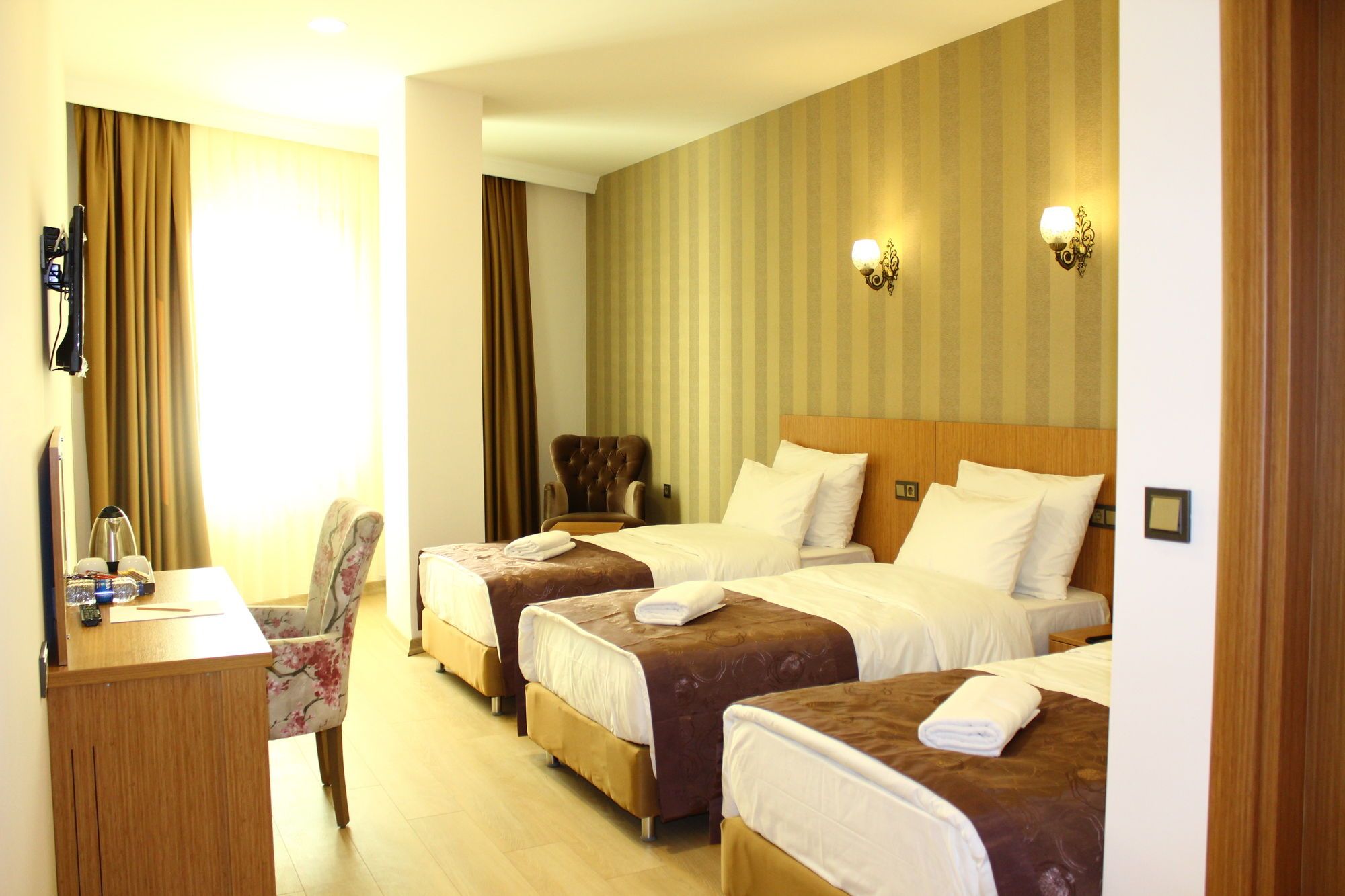 A hotel room with two beds, a desk, and a chair.