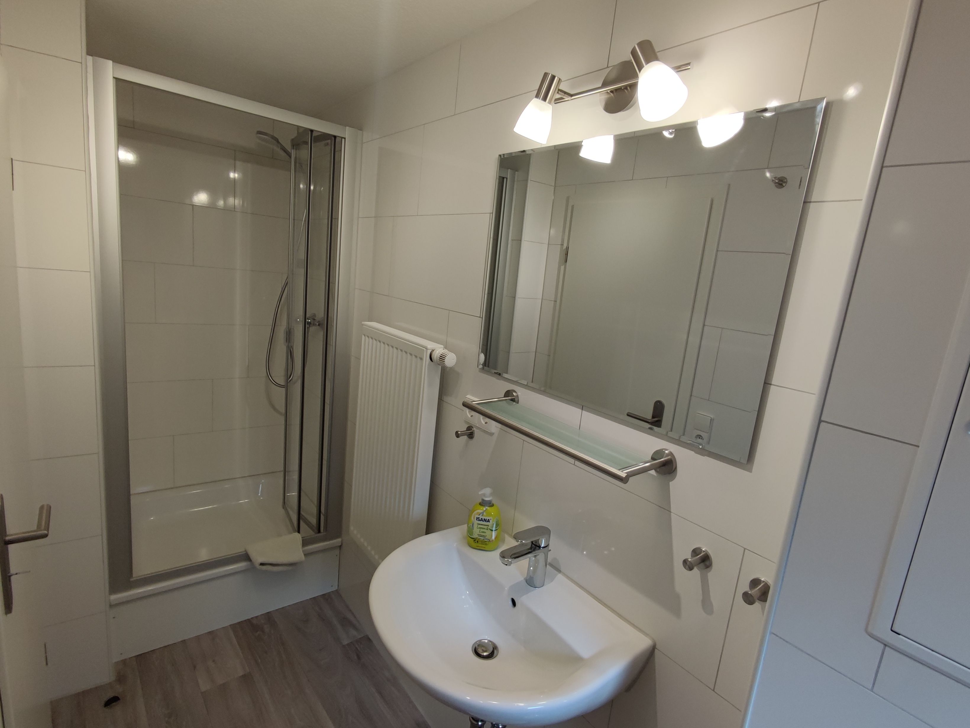 Ein modernes Badezimmer mit Glasdusche, Waschbecken mit Spiegel darüber und Handtuchwärmer.