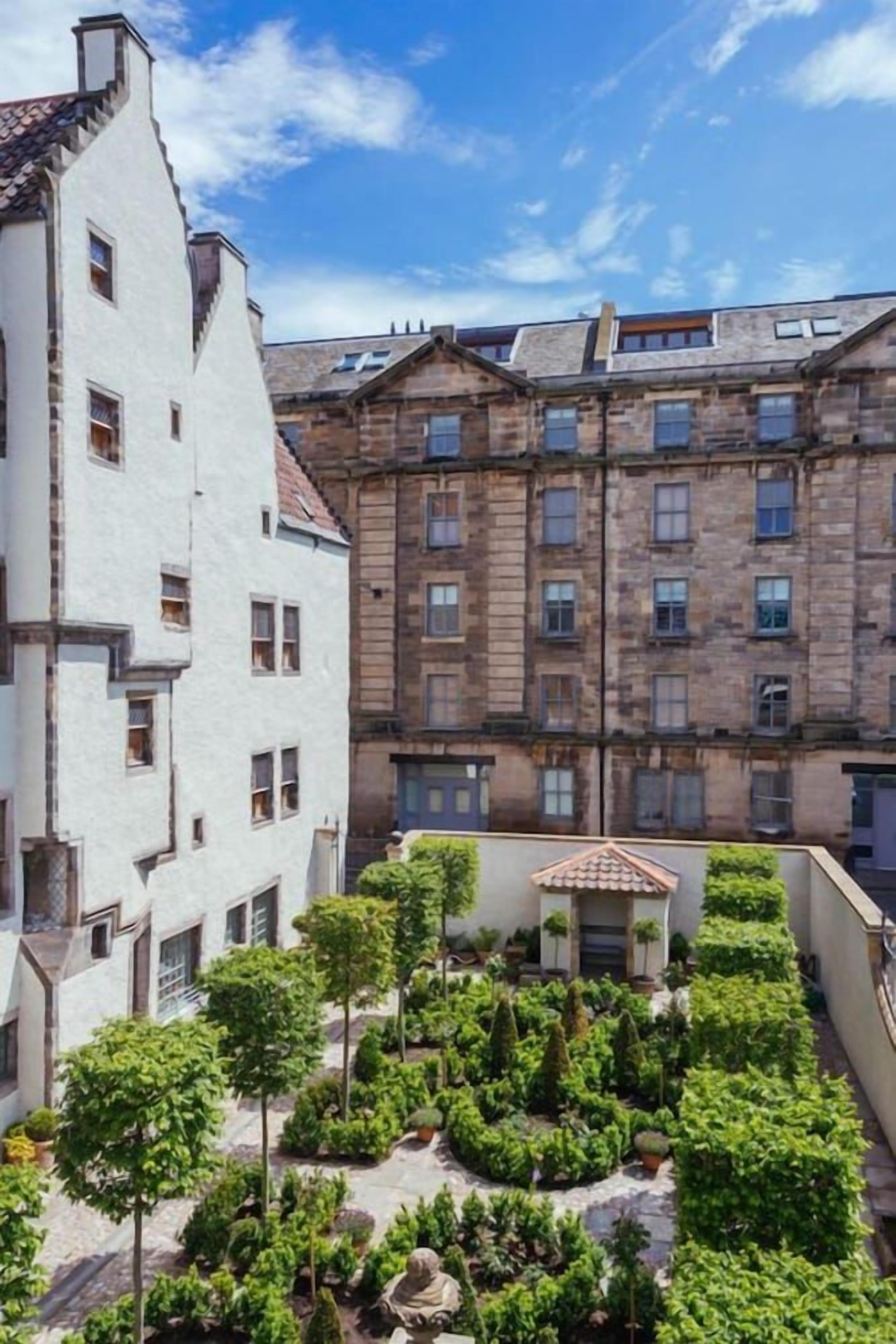 A courtyard with a central garden, surrounded by multi-story buildings with traditional architecture.