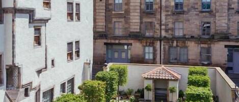 A courtyard with a central garden, surrounded by multi-story buildings with traditional architecture.