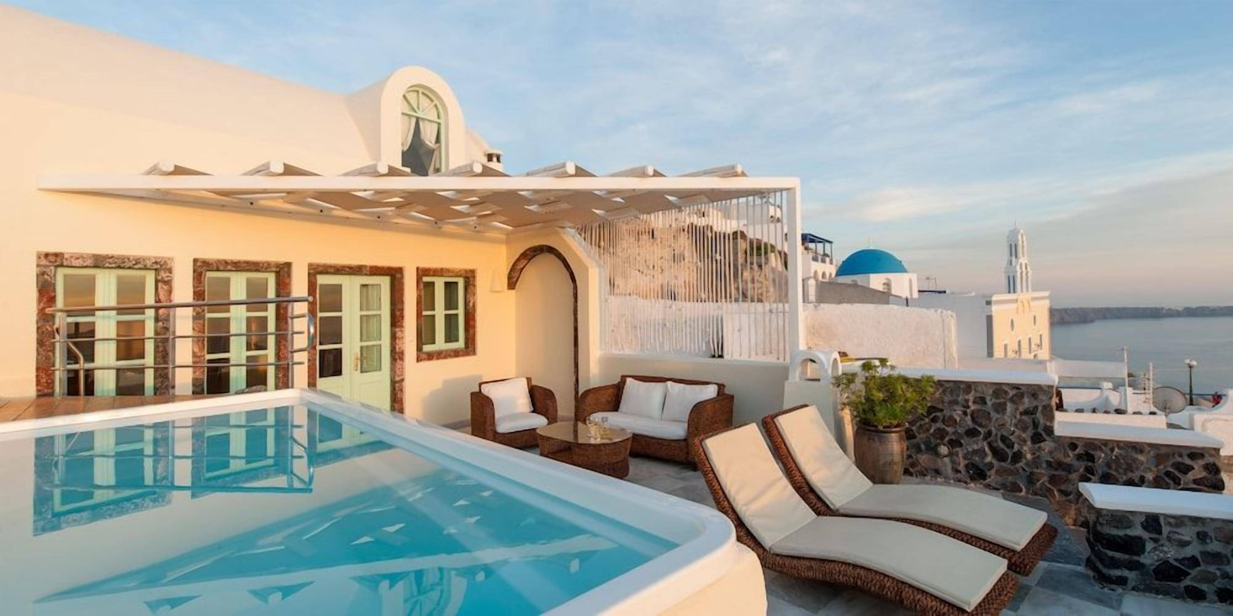 A rooftop pool area with lounge chairs and a view of the sea.