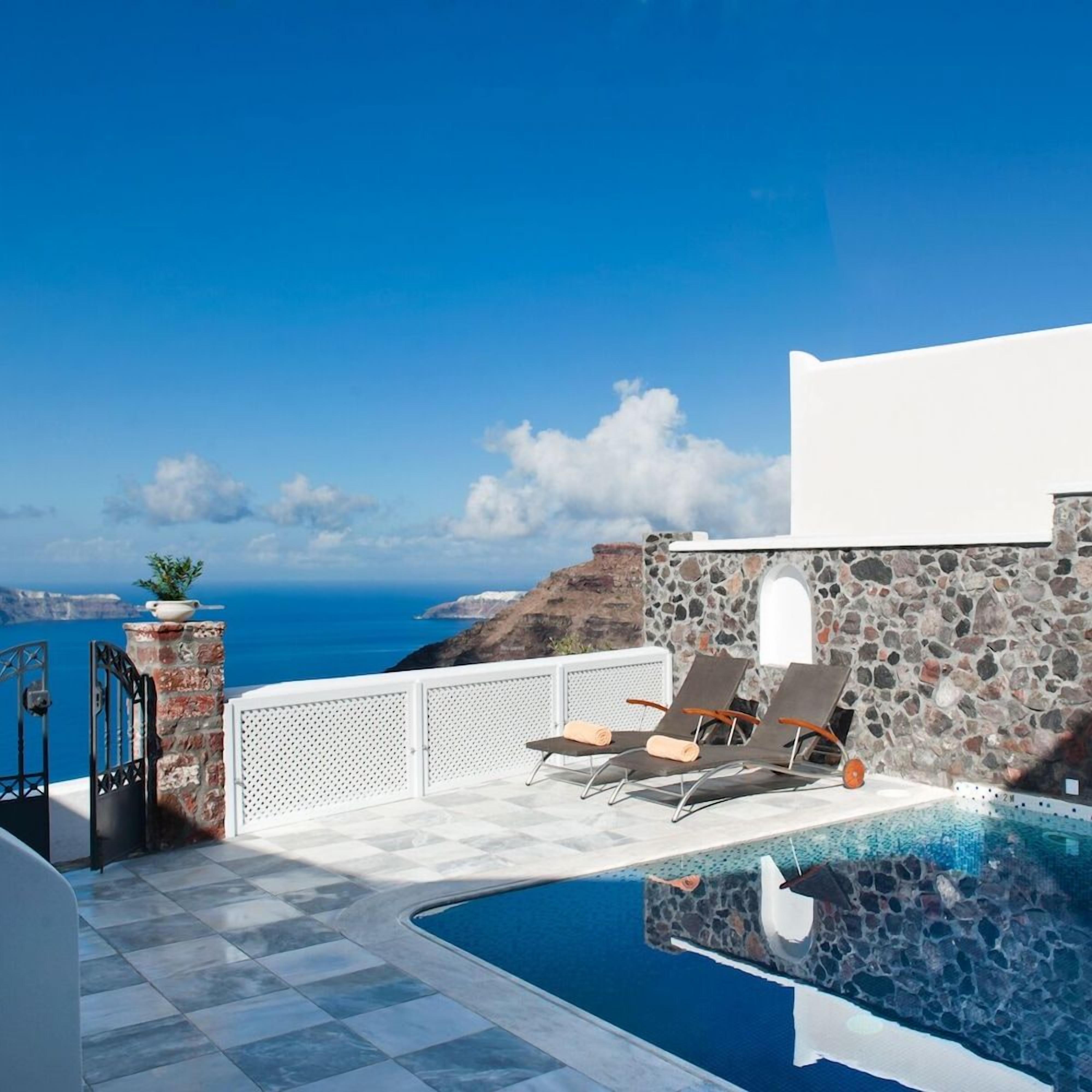 Área de piscina com espreguiçadeiras e vista para o mar.