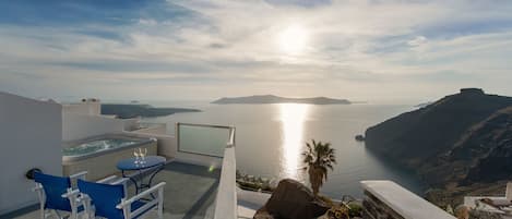 Una terraza con vistas al mar, un jacuzzi y una mesa con sillas.