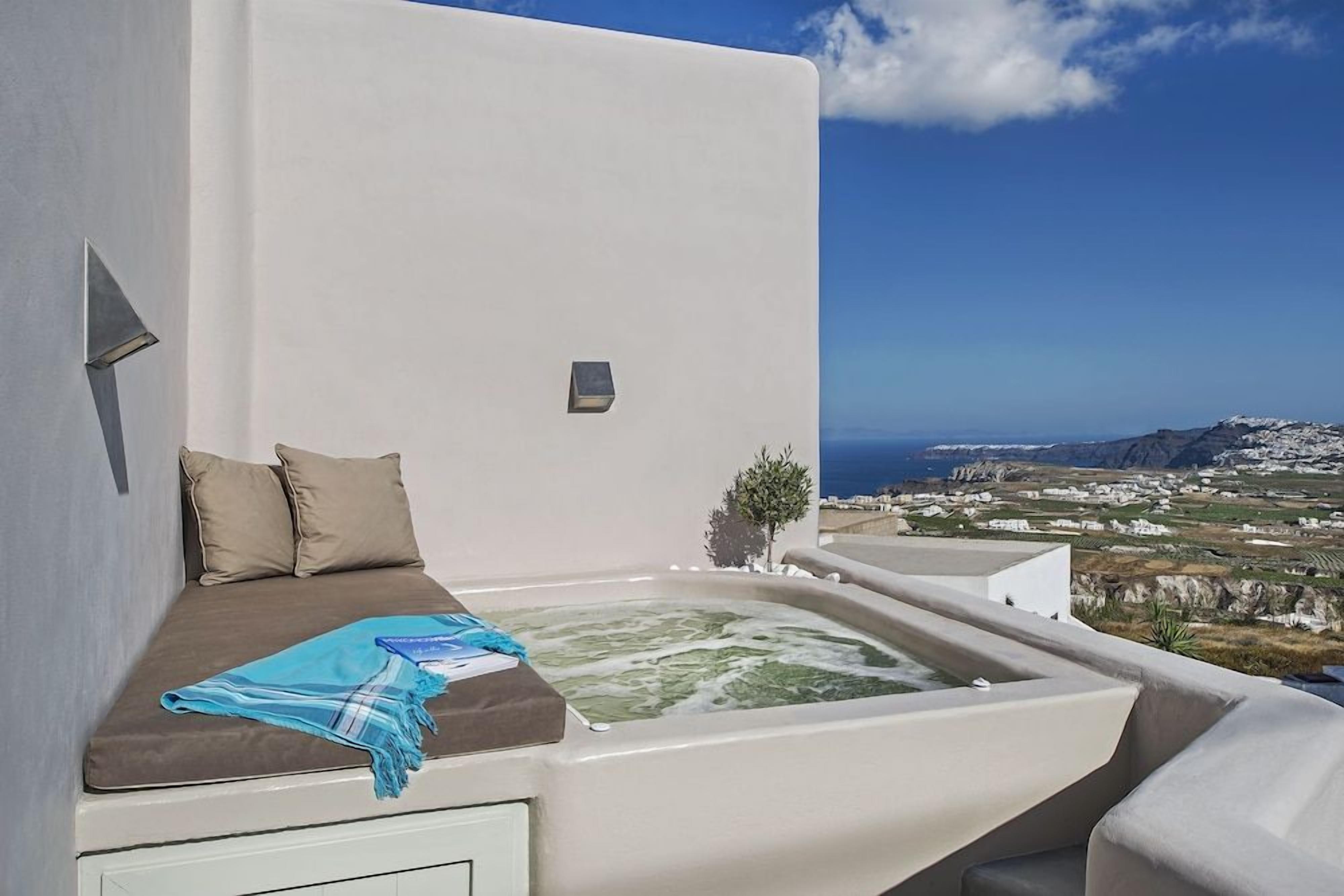 A room with a bed, a small hot tub, and a view of the landscape.