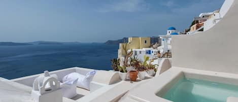 A seaside view with a clear sky, a body of water, and a building with white and blue architecture.