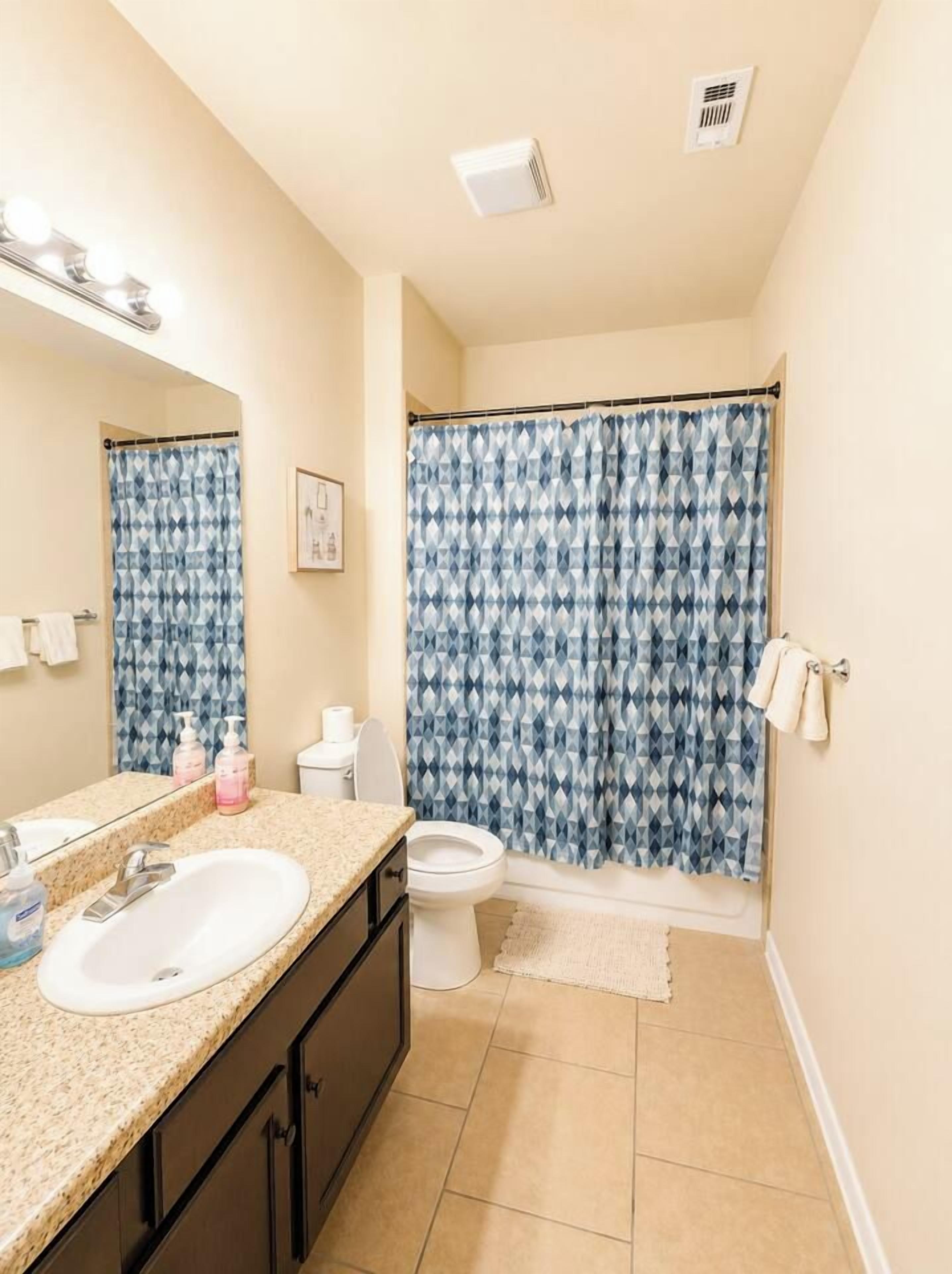 Un baño con lavamanos, espejo e inodoro.