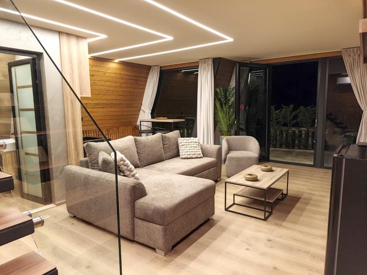 A modern living room with a sectional sofa, a coffee table, and a glass partition.