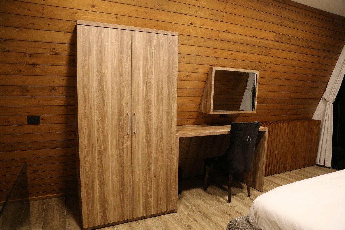 Ein Zimmer mit einem Holzschrank, einem Schreibtisch mit Stuhl und einem Bett.