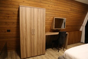 A room with a wooden wardrobe, a desk with a chair, and a bed. - Le Sommet Bungalows (Fghal)