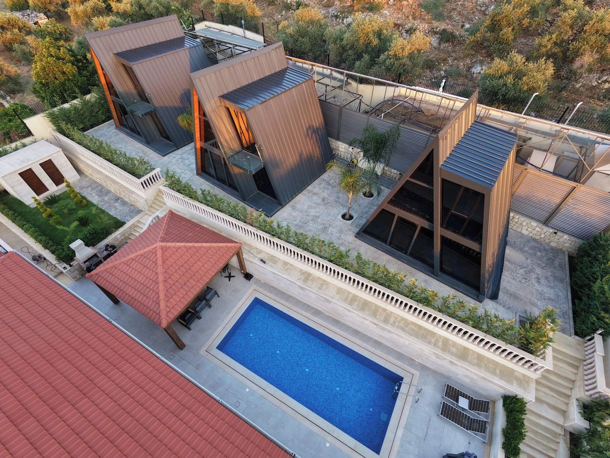 A modern residential complex with a swimming pool, multiple buildings, and a red-roofed structure.
