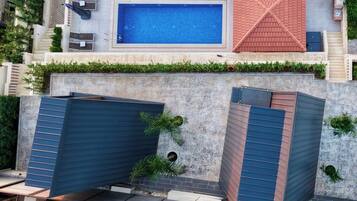 A rooftop pool with a blue interior, surrounded by a red roof and a stone wall.