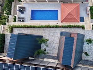 Una piscina en la azotea con interior azul, rodeada por un techo rojo y una pared de piedra.