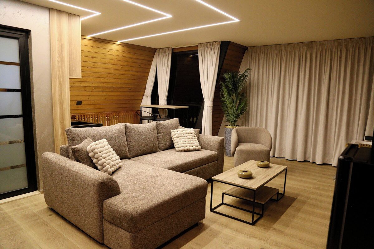 A modern living room with a sectional sofa, a small table, and a potted plant.