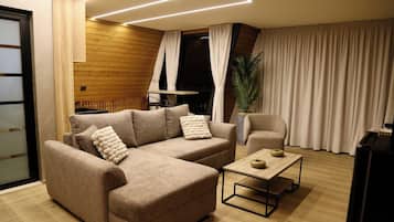A modern living room with a sectional sofa, a small table, and a potted plant.