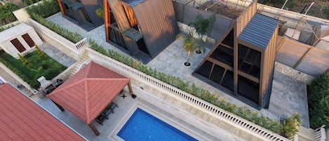 Un complejo residencial moderno con varias edificaciones, una piscina y una estructura de techo rojo.