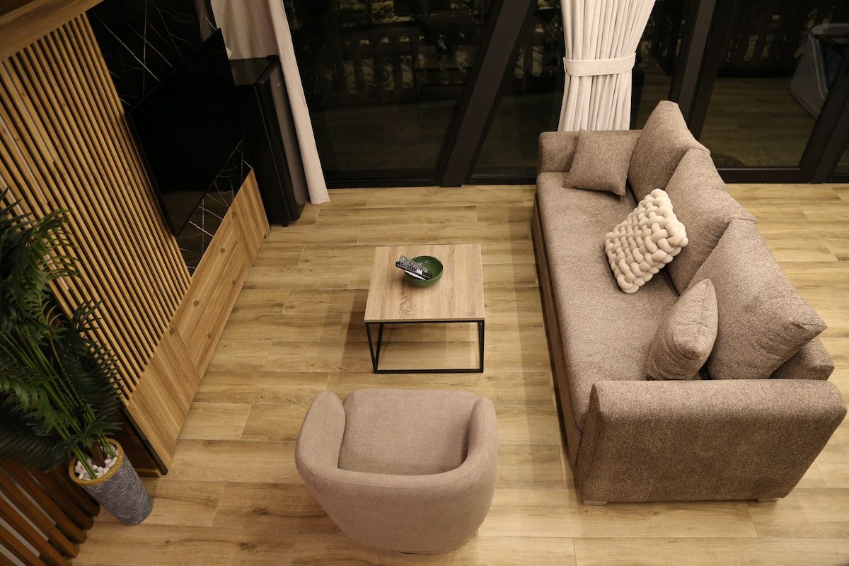 Un salon moderne avec un canapé, un petit fauteuil, une table basse et une plante en pot.