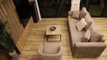 Un salon moderne avec un canapé, un petit fauteuil, une table basse et une plante en pot.