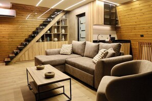 Una sala moderna con un sofá modular, una mesa de centro y una escalera con estanterías integradas.