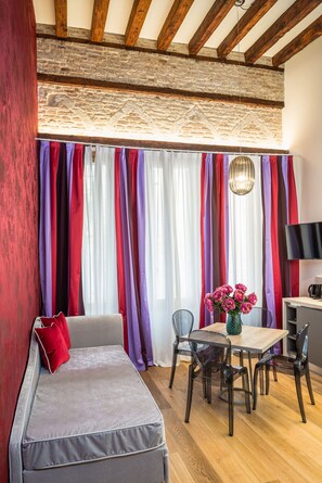 A modern living room with a sofa, a dining table with chairs, and a TV. - Polo's Treasures (Venice)