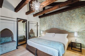 Un dormitorio con una cama grande, un espejo, una araña y un papel pintado con diseño.