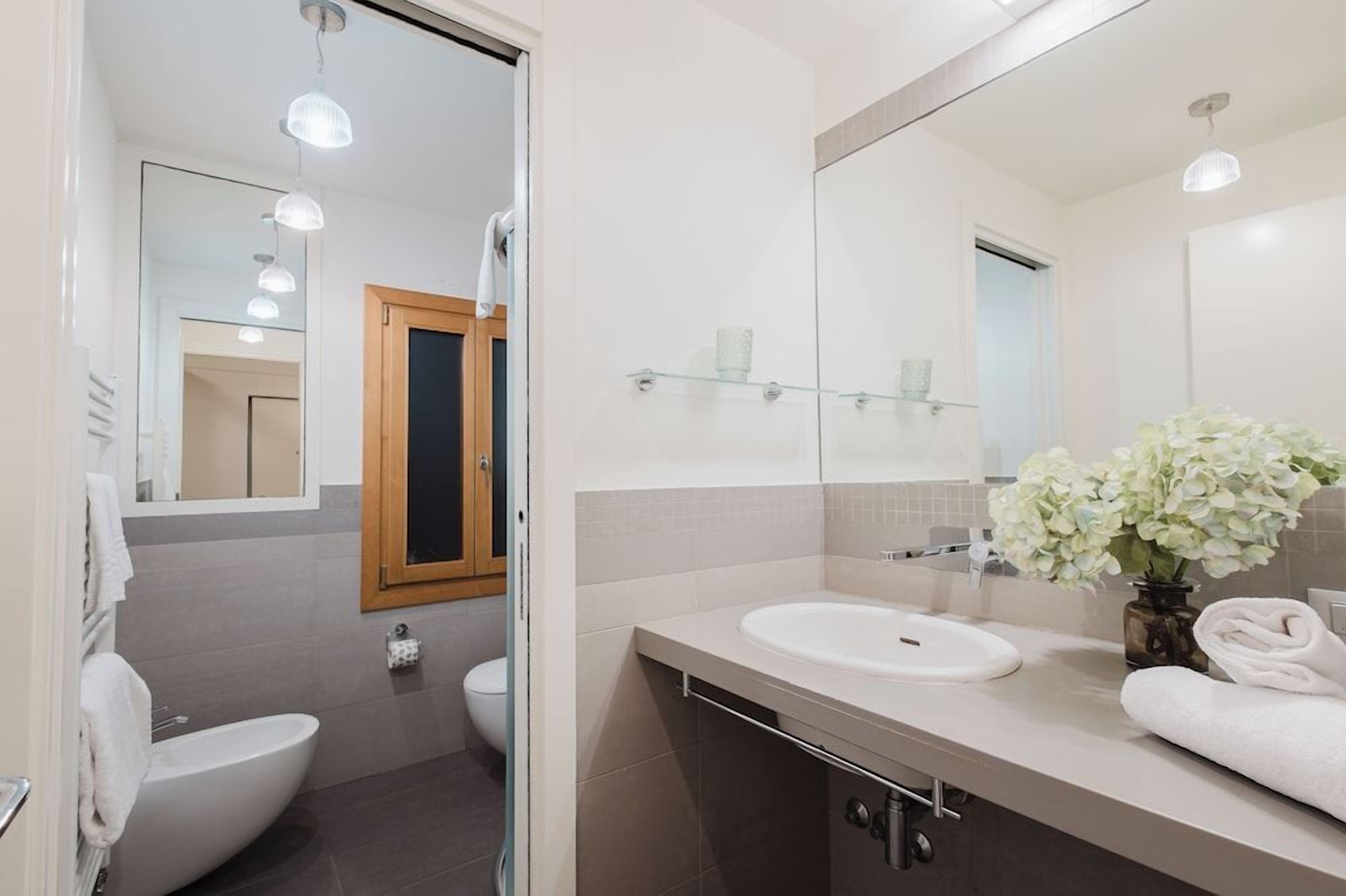Et moderne badeværelse med vask, spejl og toilet.