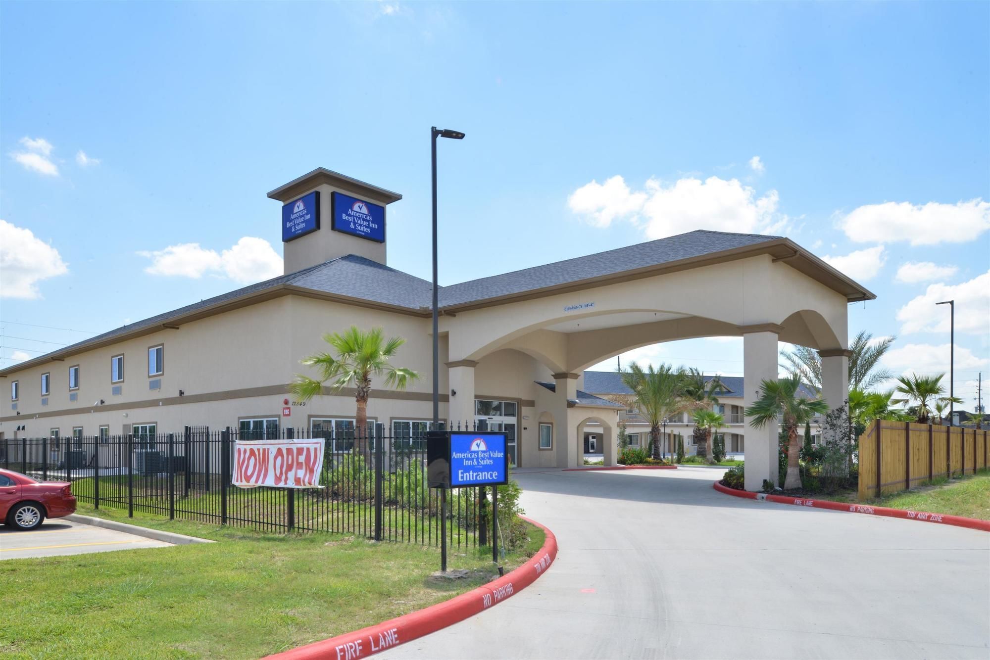 A hotel entrance with a clear sign indicating 'NOW OPEN' and a 'Fire Lane' marking.