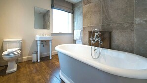 Un baño moderno con una bañera independiente, un inodoro y un lavamanos.